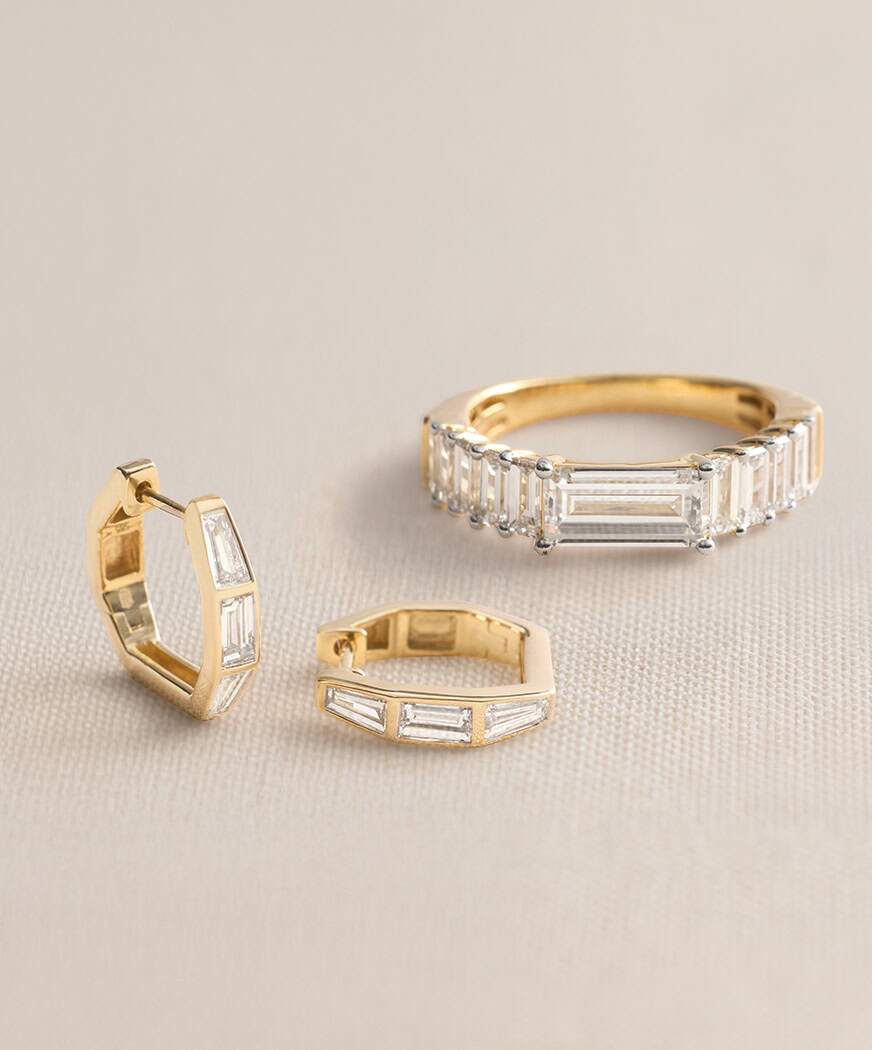 Gold jewelry set with ring and earrings featuring baguette diamonds.