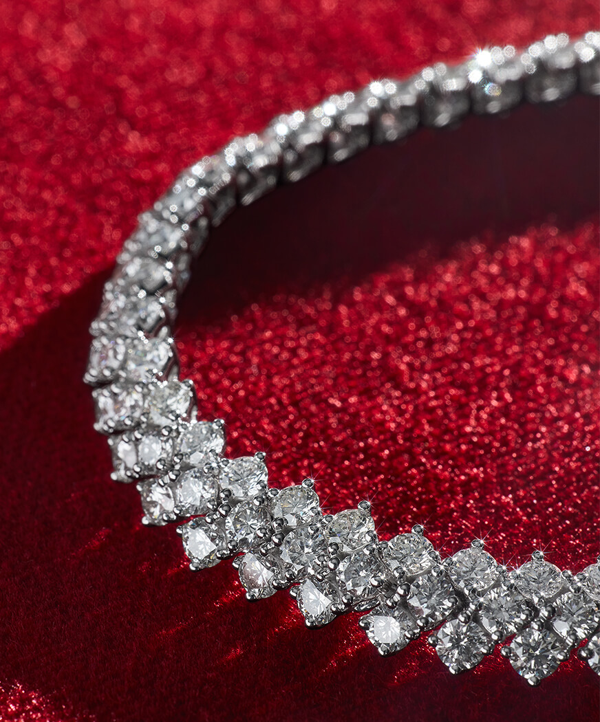 Close-up of a sparkling diamond tennis necklace on a red background