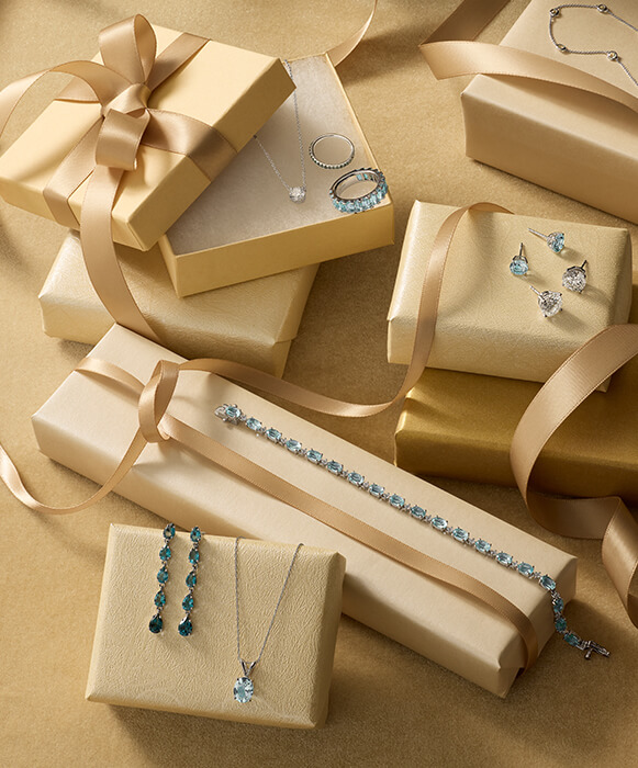 Gemstone and diamond necklaces, earrings, and bracelets atop gift boxes