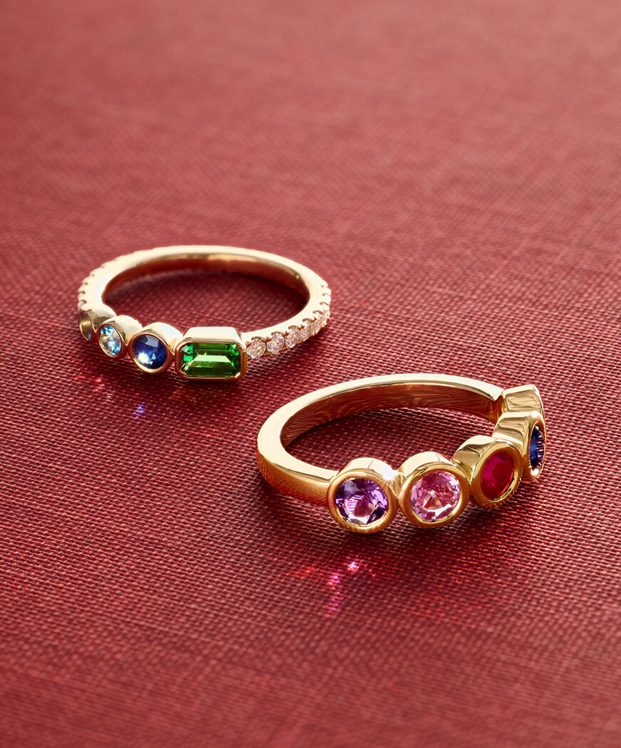 Elegant gold rings adorned with colorful gemstones on a red background